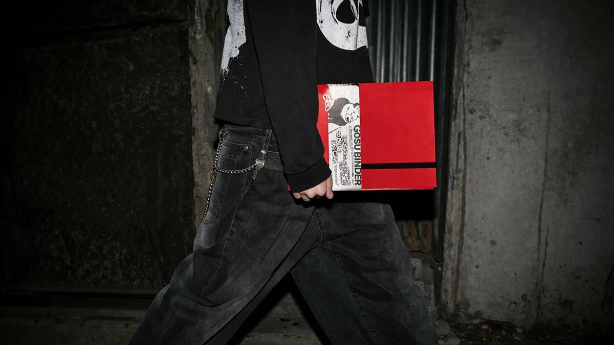 Persona caminando por la calle con un binder GOSU rojo en la mano